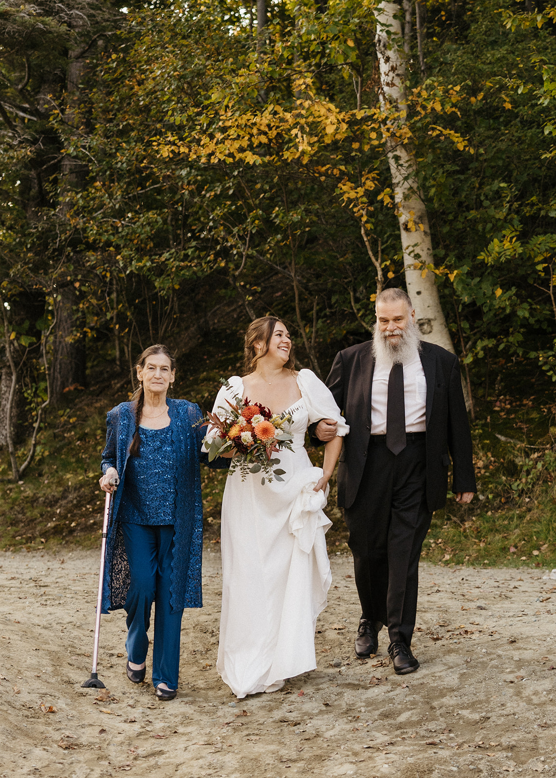 Bride walking down the isle with her mom and dad at Echo Lake State Park in New Hampshire