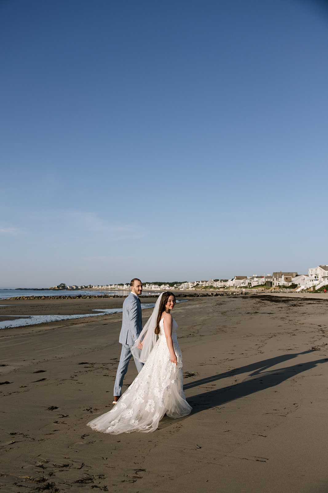 Bride and groom walk on the seacoast of New Hampshire