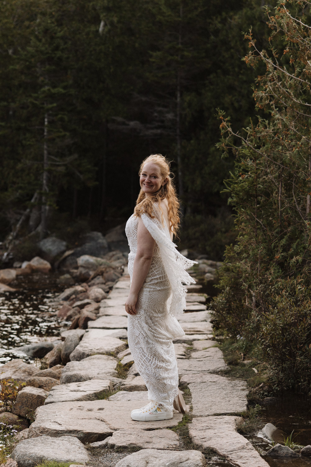 bride poses in the dreamy Acadia national park with her boho wedding dress 
