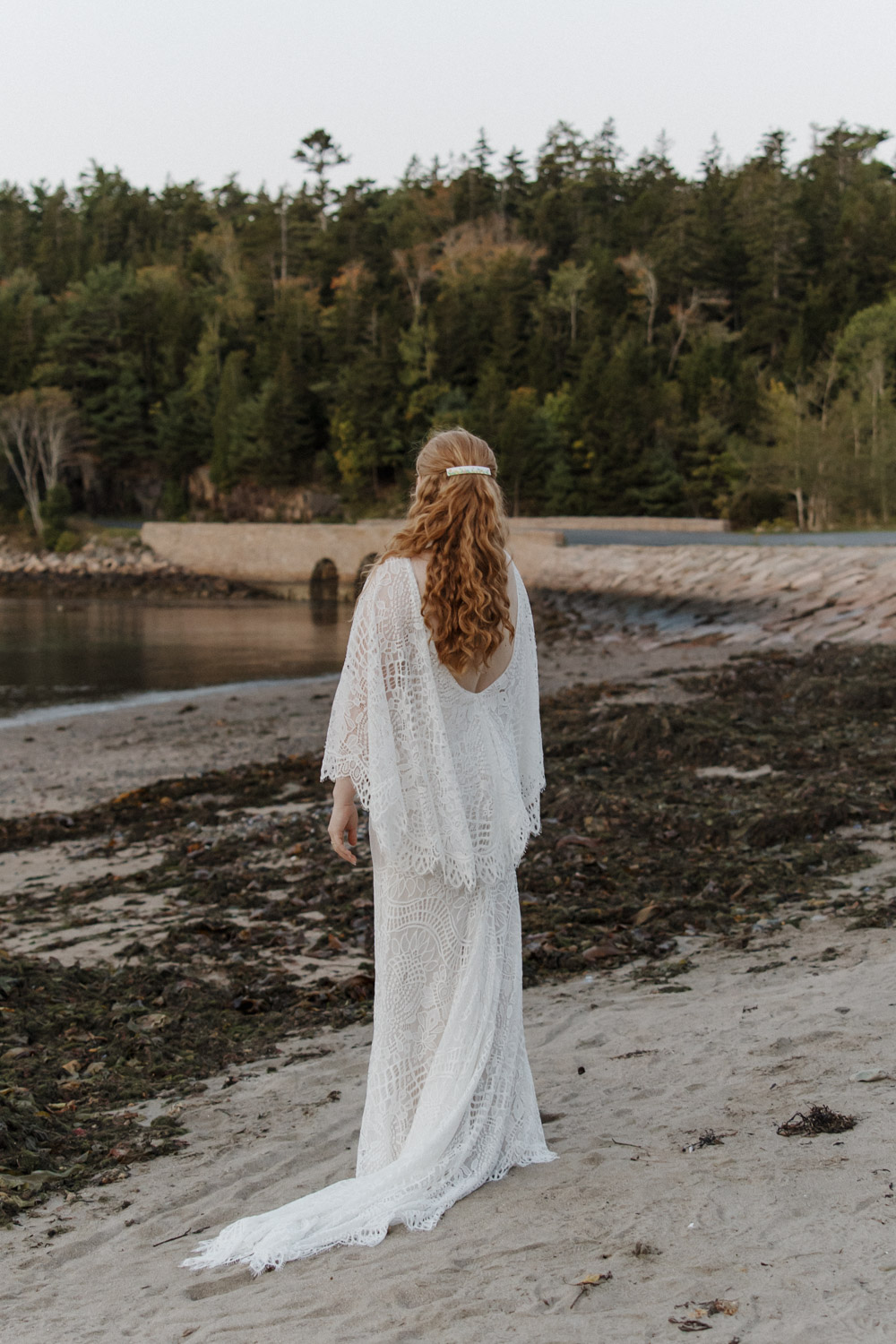 bride poses on the beach in Acadia, Maine