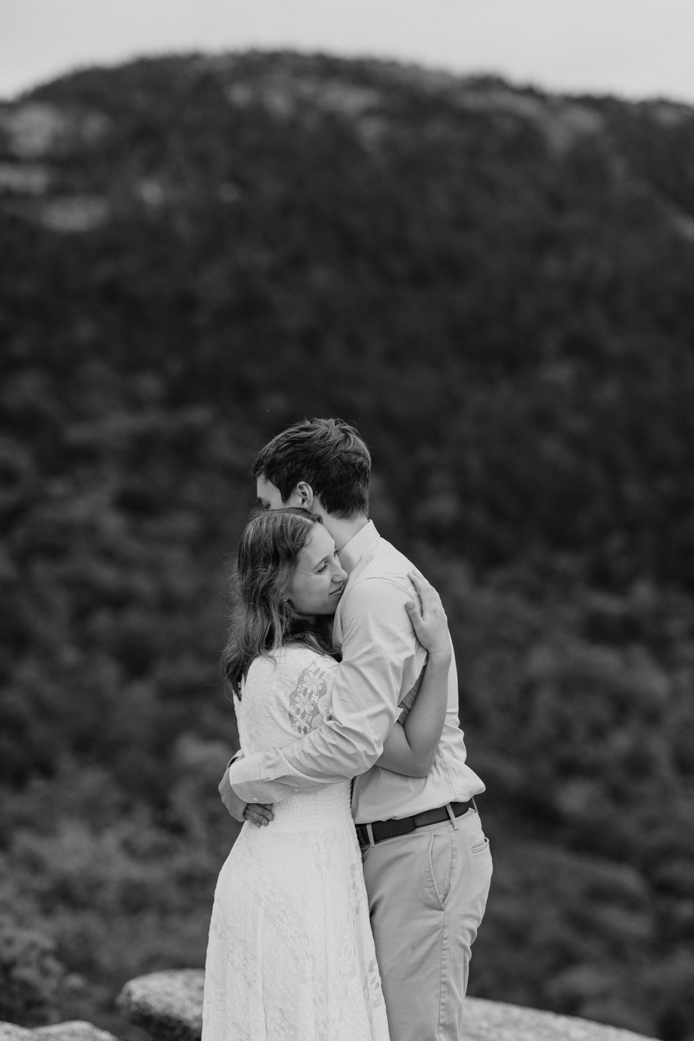 couple share a hug with the stunning valley view in the background