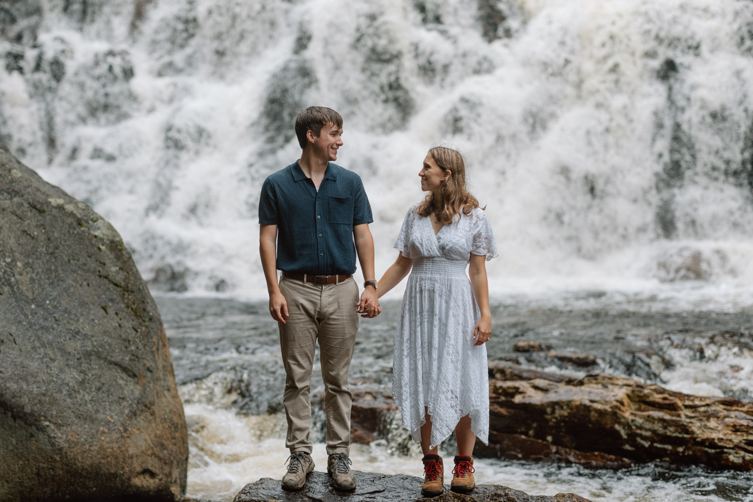 beautiful couple pose together at the base of a waterfall during their White mountain engagement photos 