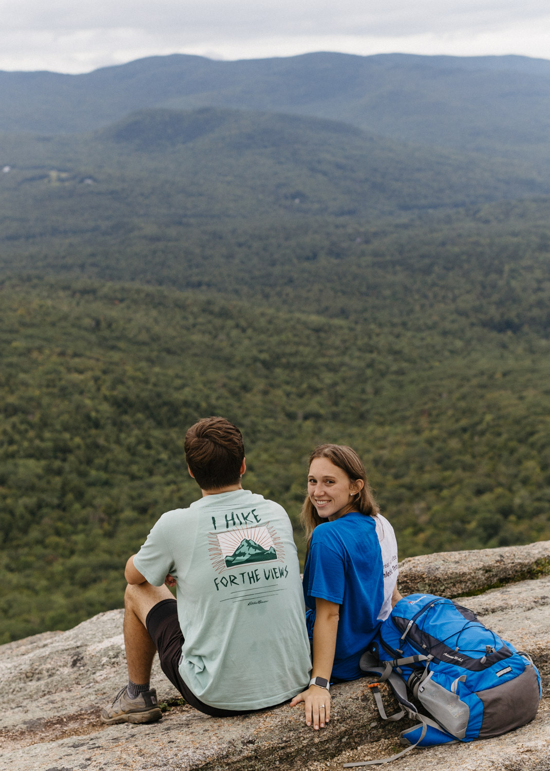 couple pose together overlooking the stunning valley below during their White mountain hiking engagement photoshoot