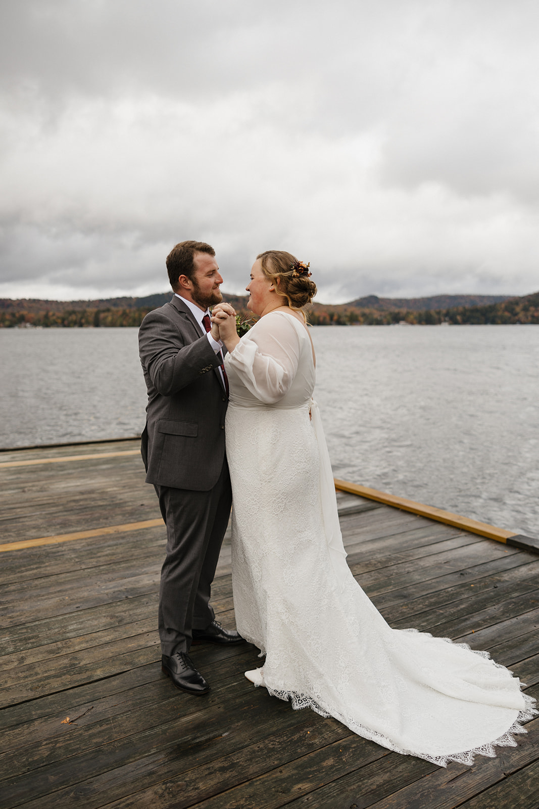 bride and groom share an emotional first look photo session on a lake dock