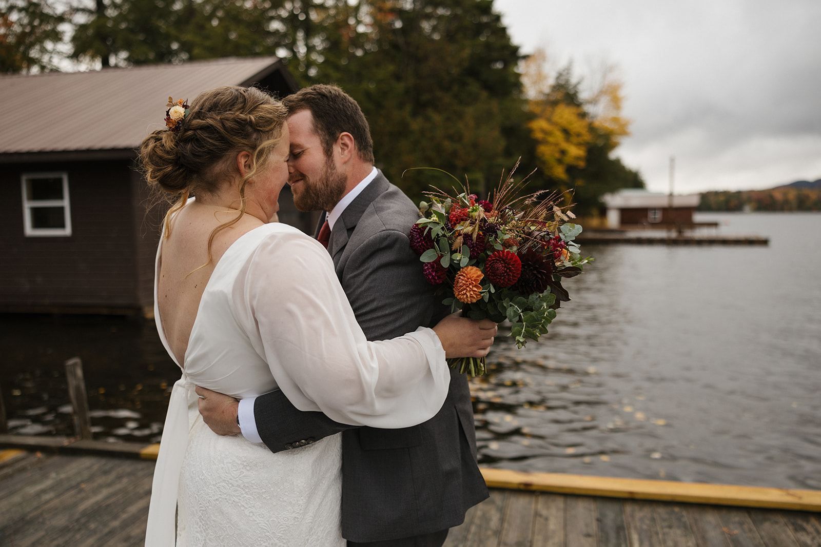 bride and groom share an emotional first look photo session on a lake dock