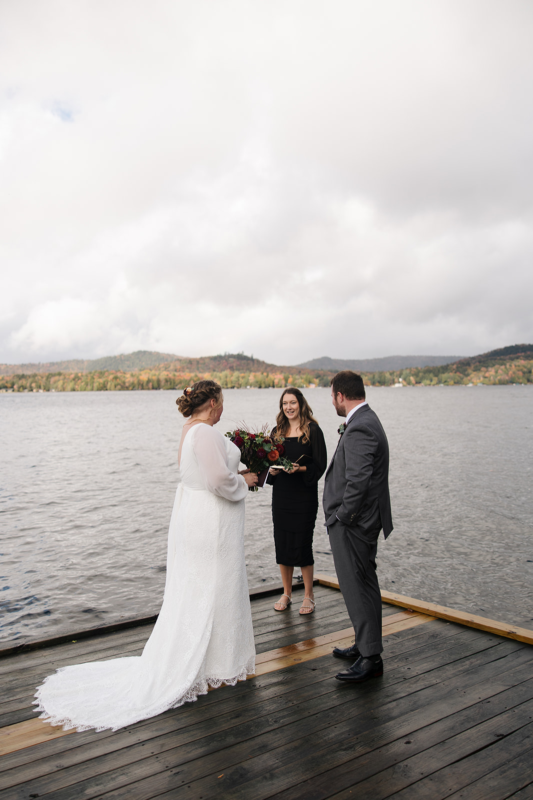 bride and groom surrounded by friends and family on a lake dock say I do