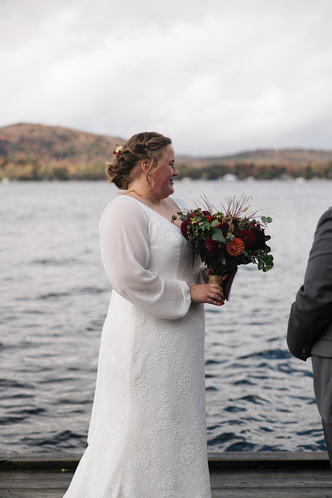 bride and groom surrounded by friends and family on a lake dock say I do