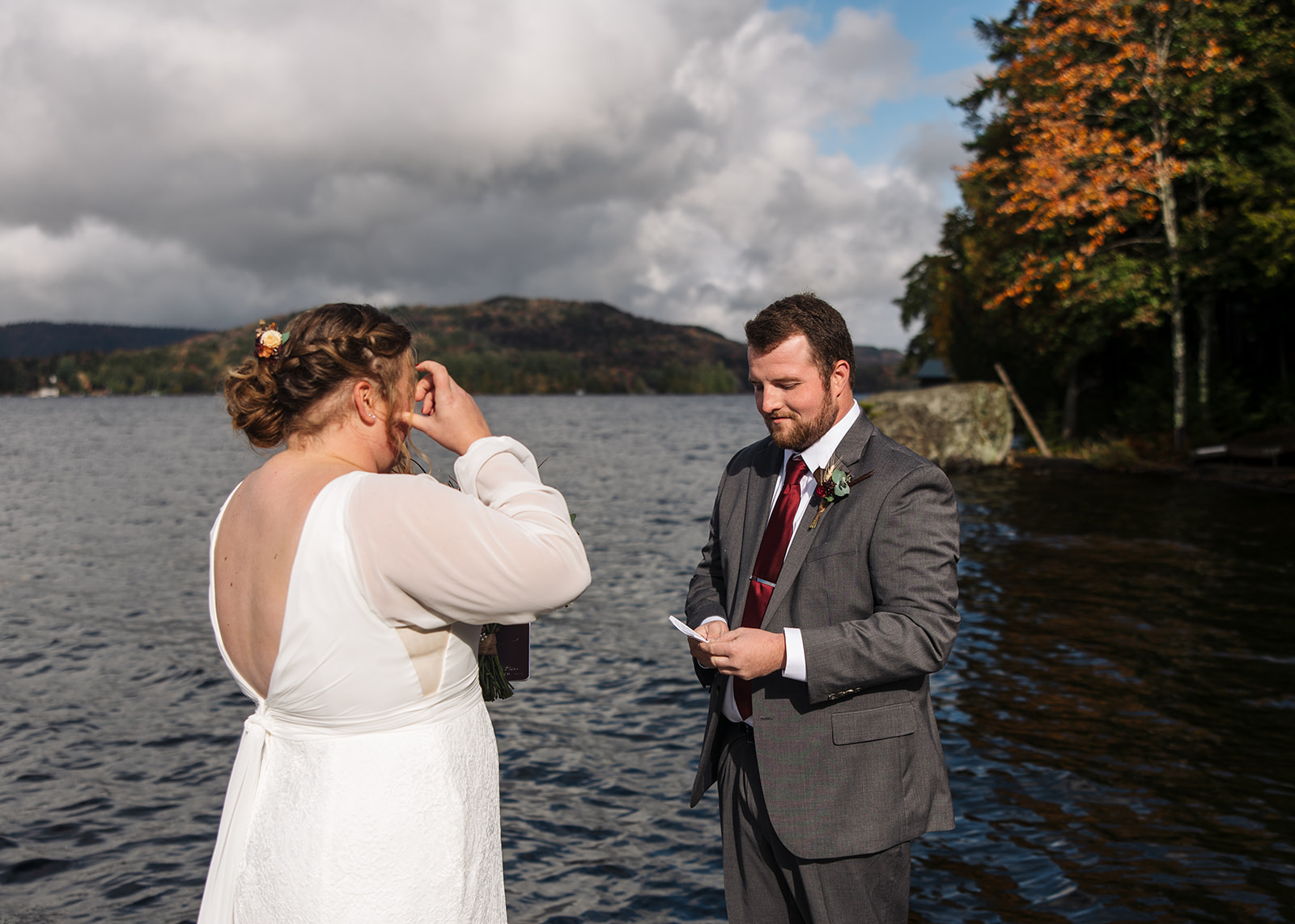 bride and groom surrounded by friends and family on a lake dock say I do