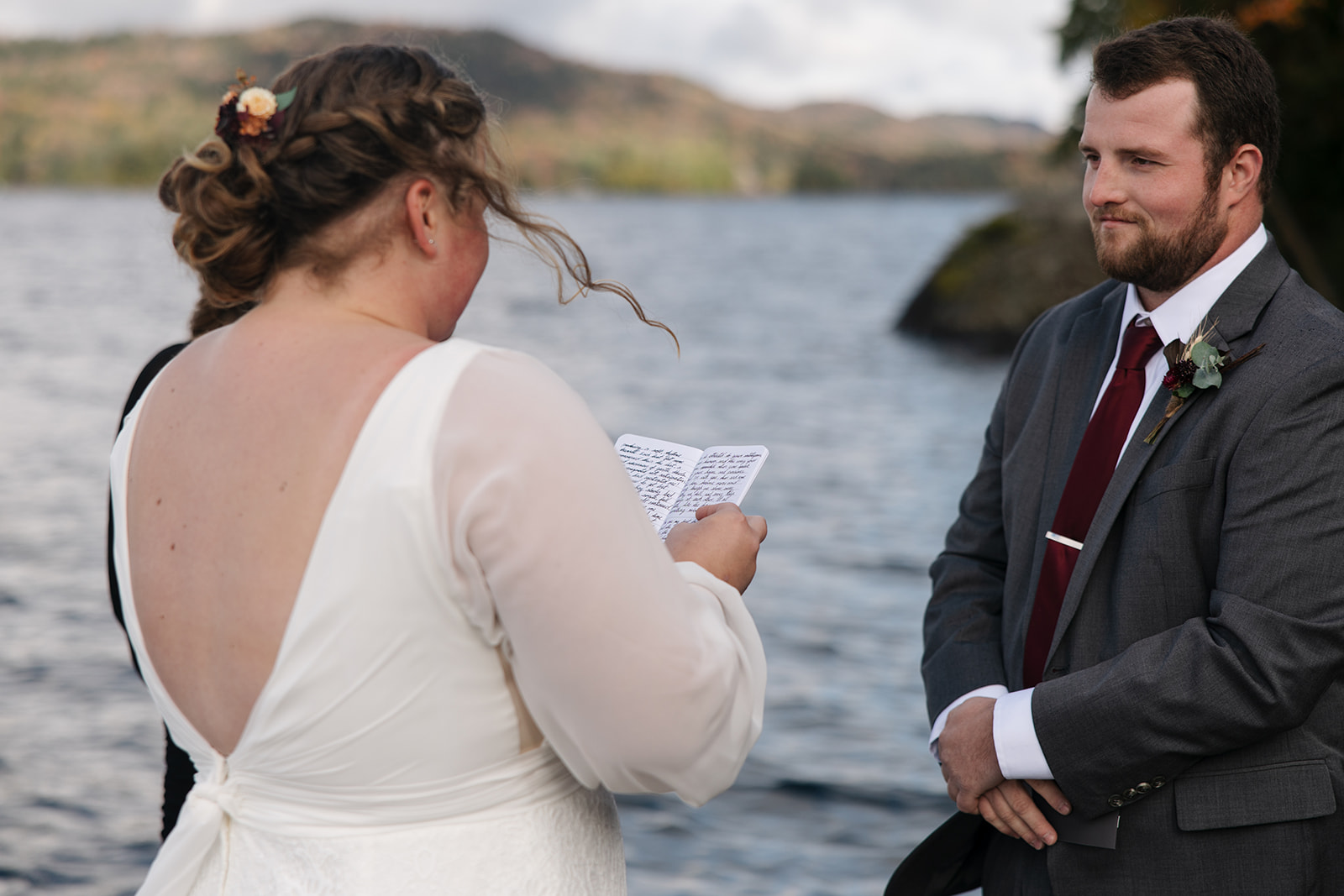 bride and groom surrounded by friends and family on a lake dock say I do