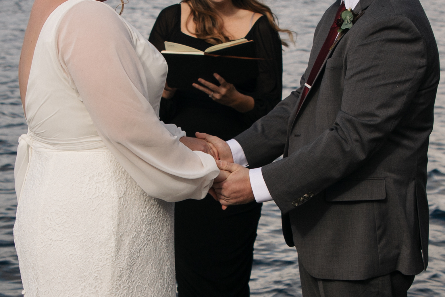 bride and groom surrounded by friends and family on a lake dock say I do