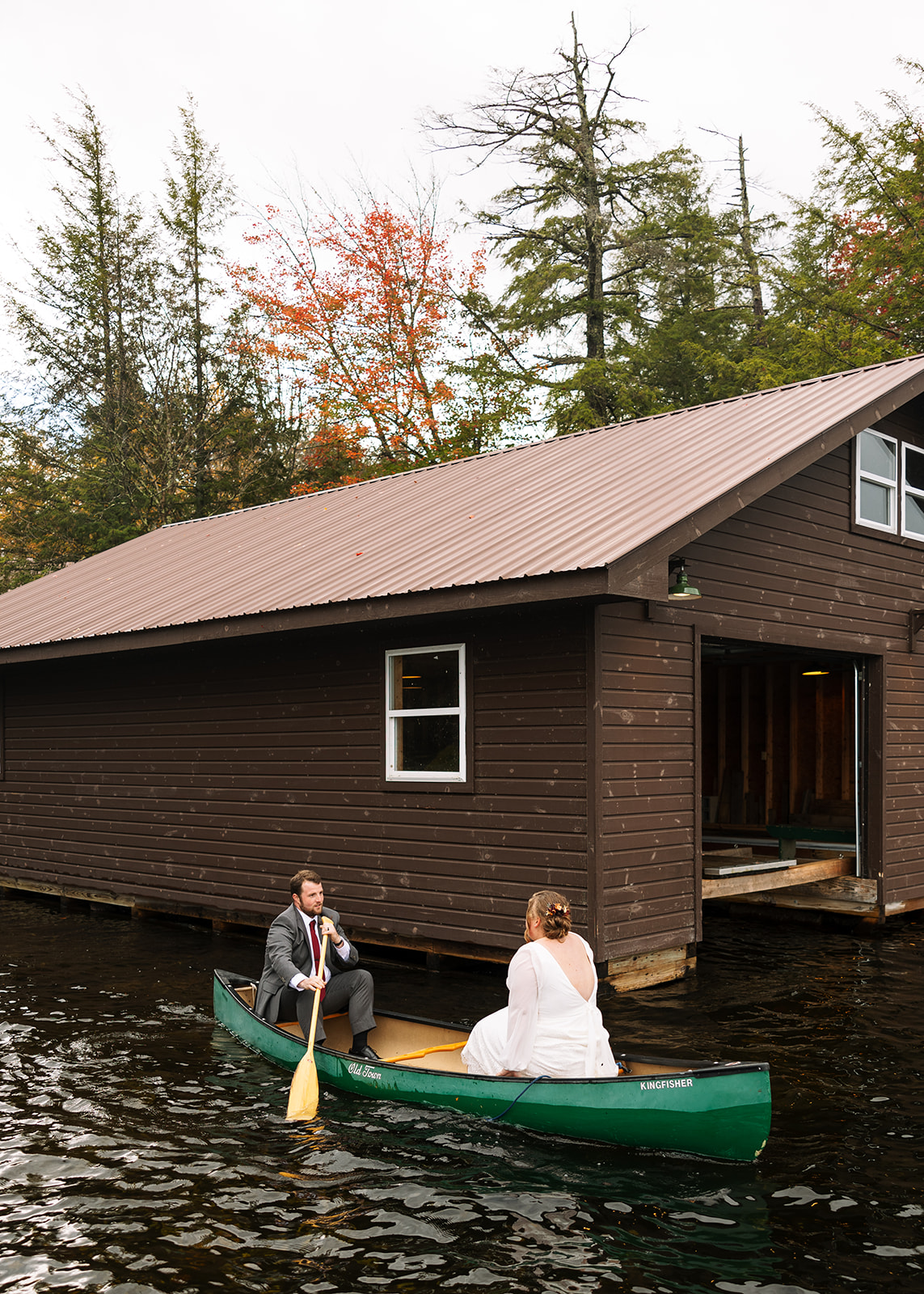 bride and groom row in a canoe after their upstate NY wedding ceremony