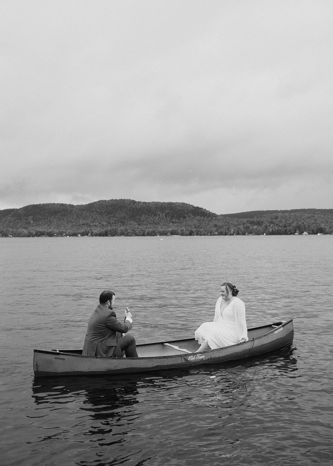 bride and groom row in a canoe after their upstate NY wedding ceremony