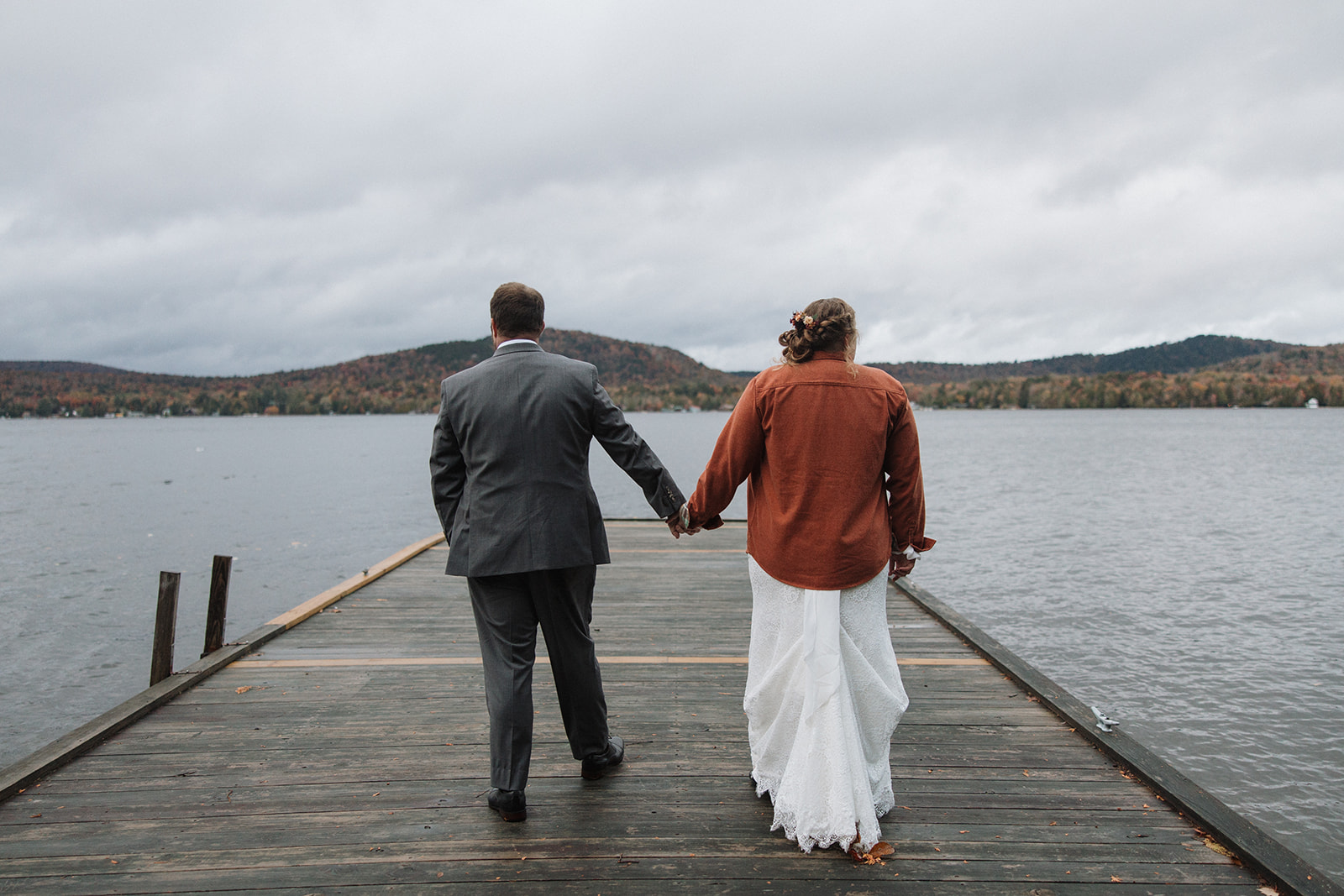 bride and groom walk on a dock together