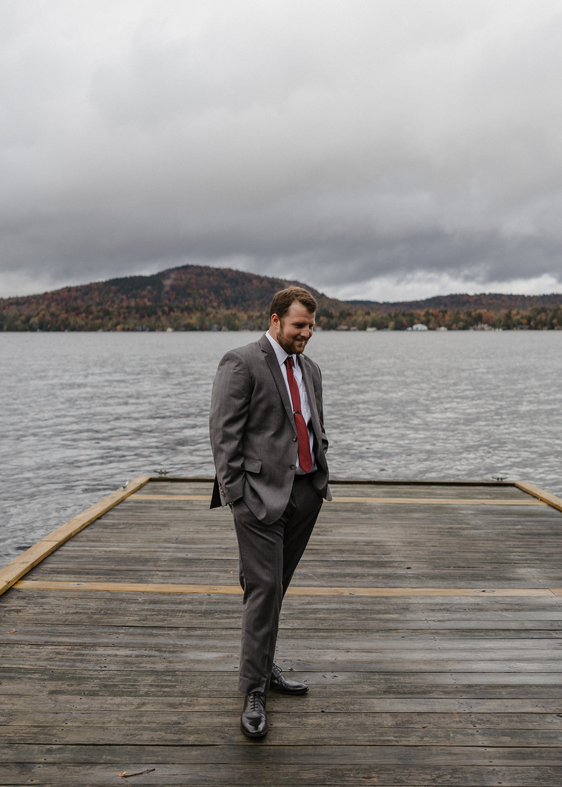 groom anxiously awaits his bride on the lake dock