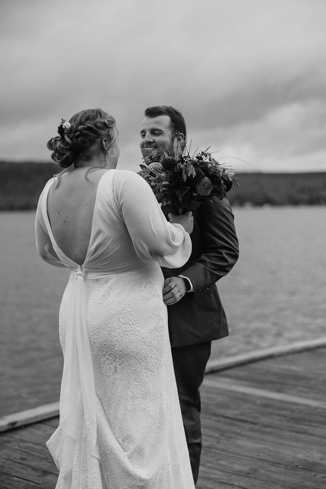 bride and groom share an emotional first look photo session on a lake dock