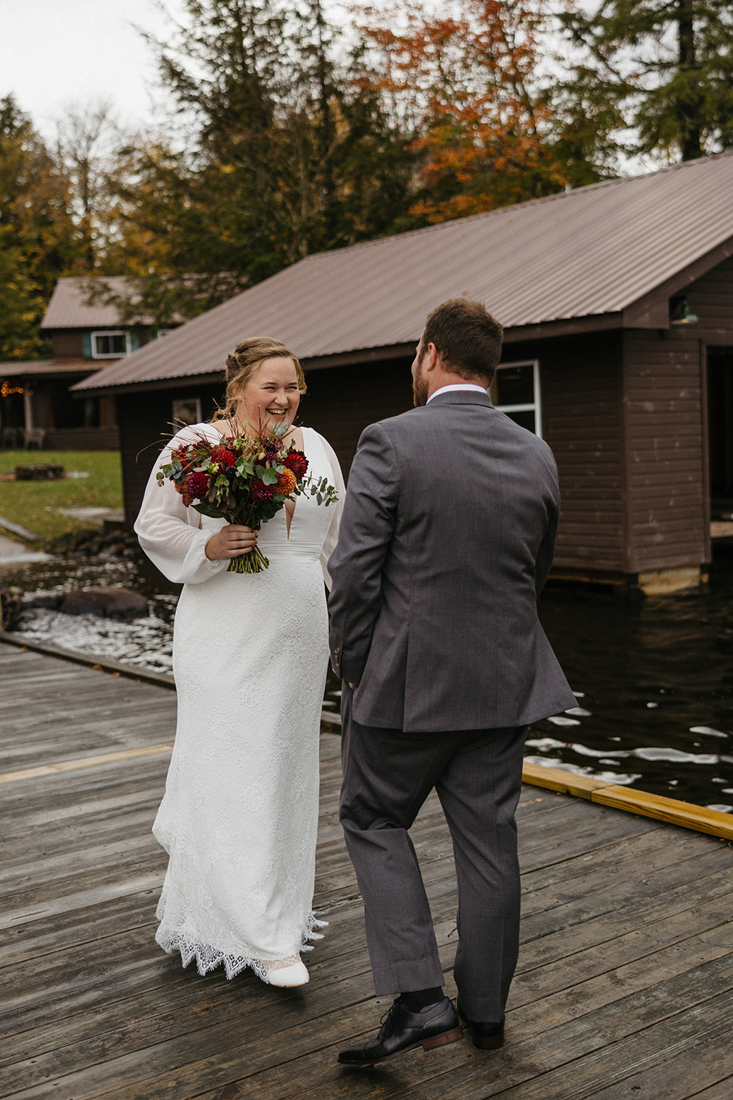 bride and groom share an emotional first look photo session on a lake dock