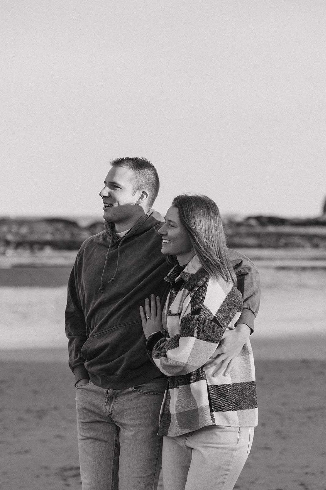 stunning couple pose on a New Hampshire beach during their East coast engagement photos