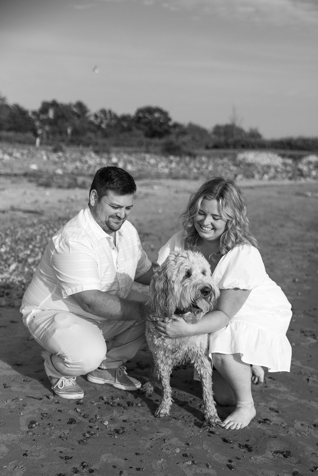 beautiful couple pose with their dog on an East Coast beach