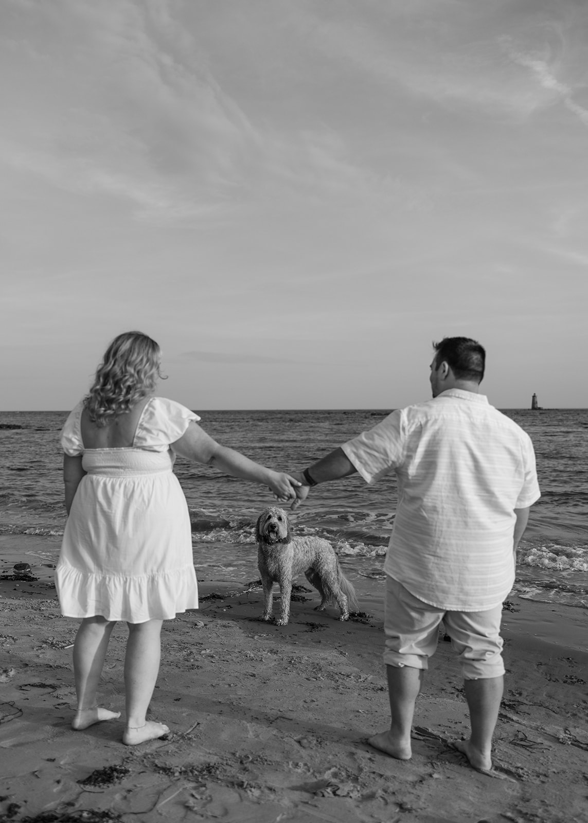 beautiful couple pose with their dog on an East Coast beach