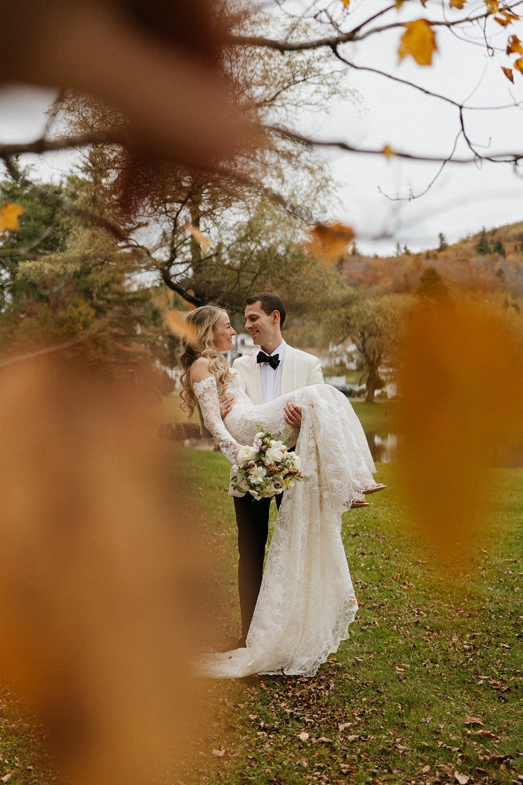 bride and groom pose for a photo through a leaf