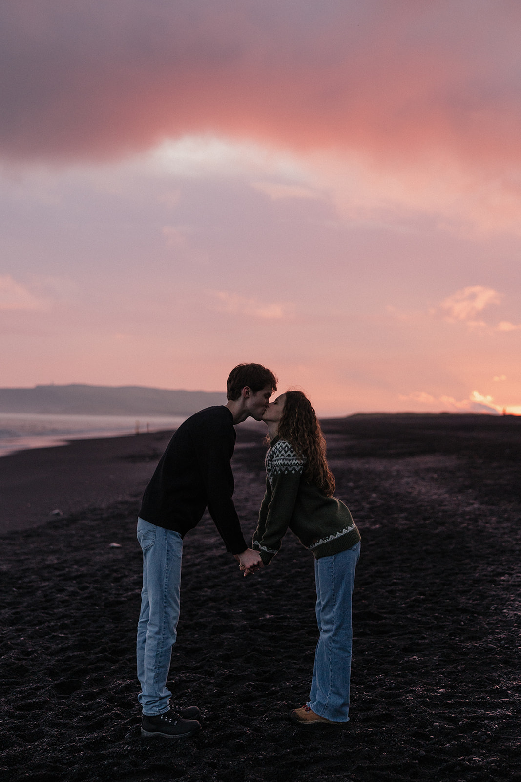 stunning couple share a kiss on the icelandic beach at sunset