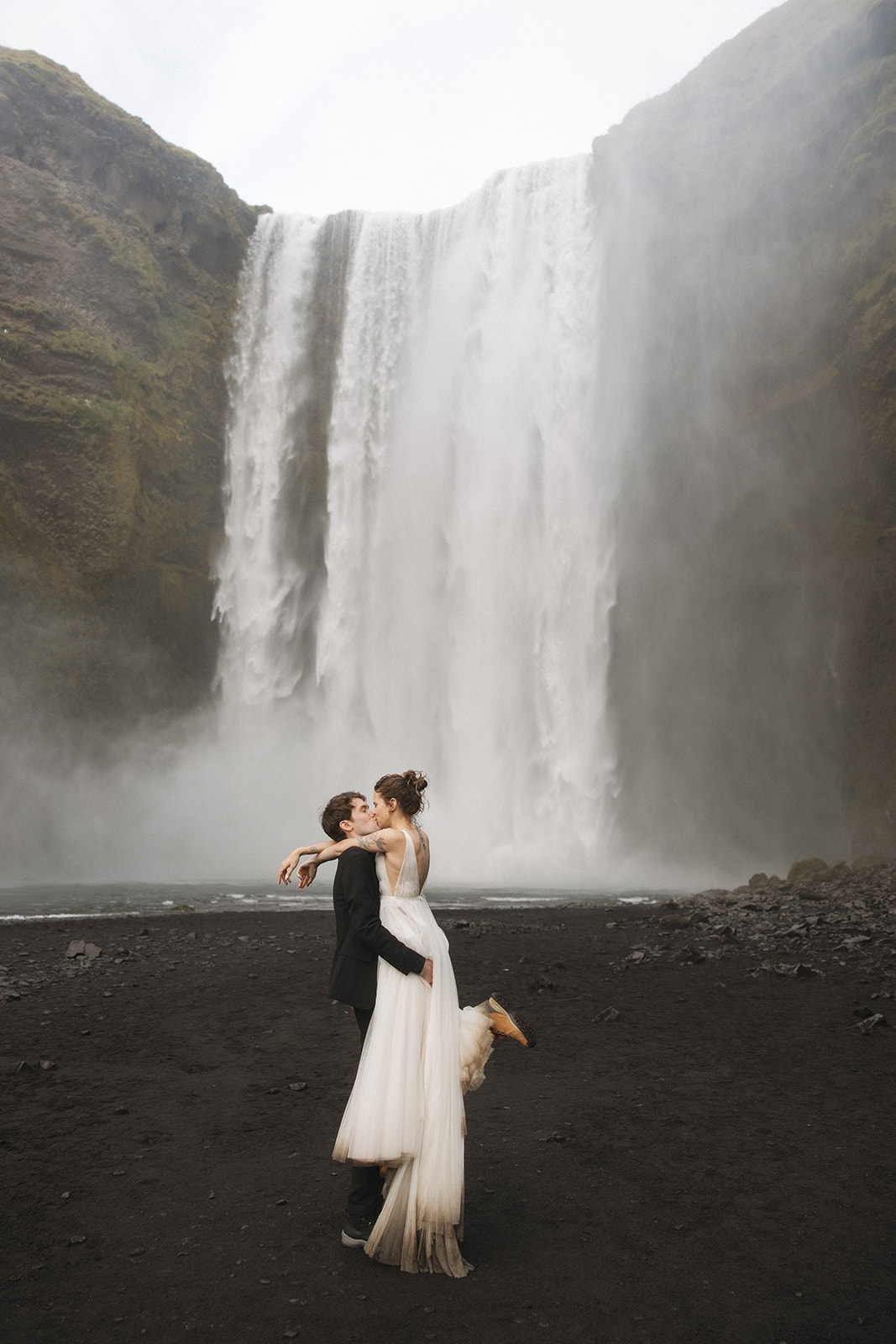 Bride and groom at the bottom of Skogafoss waterfall during their Iceland elopement