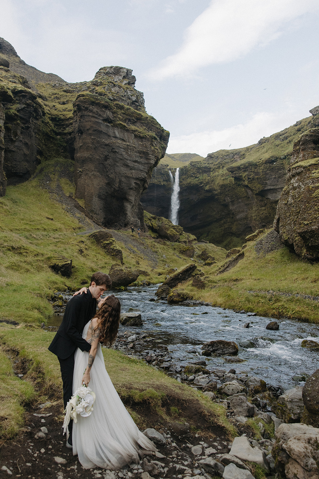 beautiful bride and groom share a kiss under the stunning waterfall in Iceland