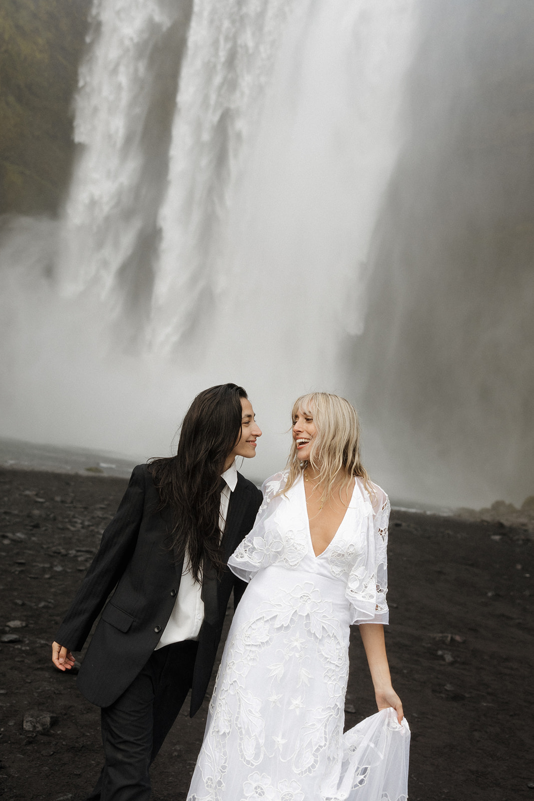 same sex couple pose at skogafoss waterfall