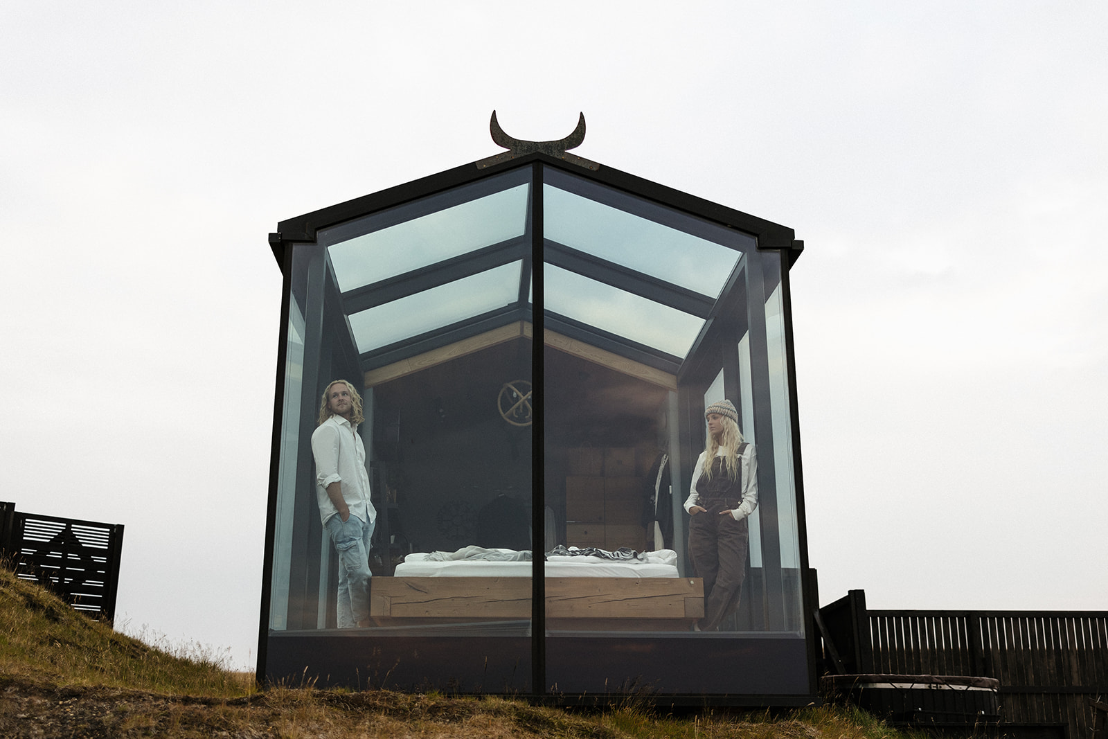 bride and groom causally pose inside of the glass house