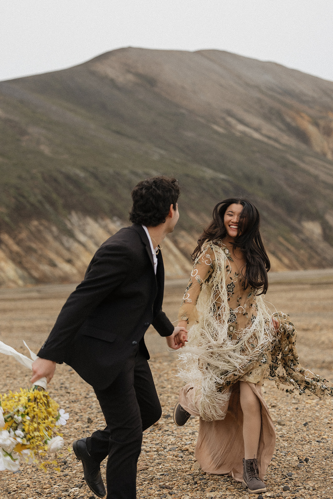 bride in a bohemian dress runs with groom during their iceland elopement portraits