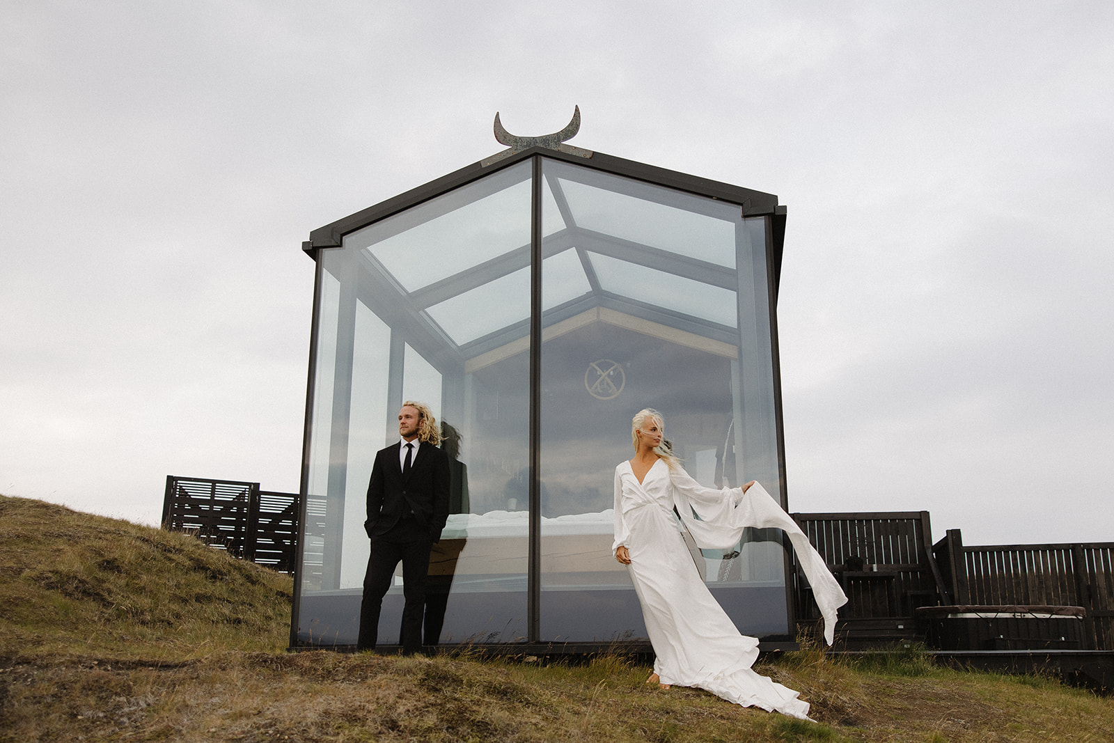 bride and groom pose in front of the glass house in iceland