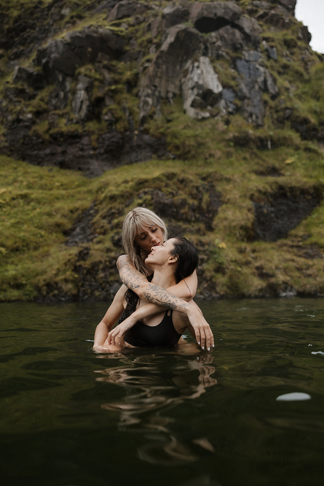 same sex couple show affection with each other in a hot springs in iceland