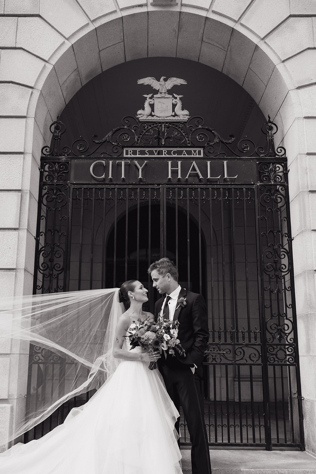 bride and groom pose in front of the Portland, Maine city hall after their dreamy wedding
