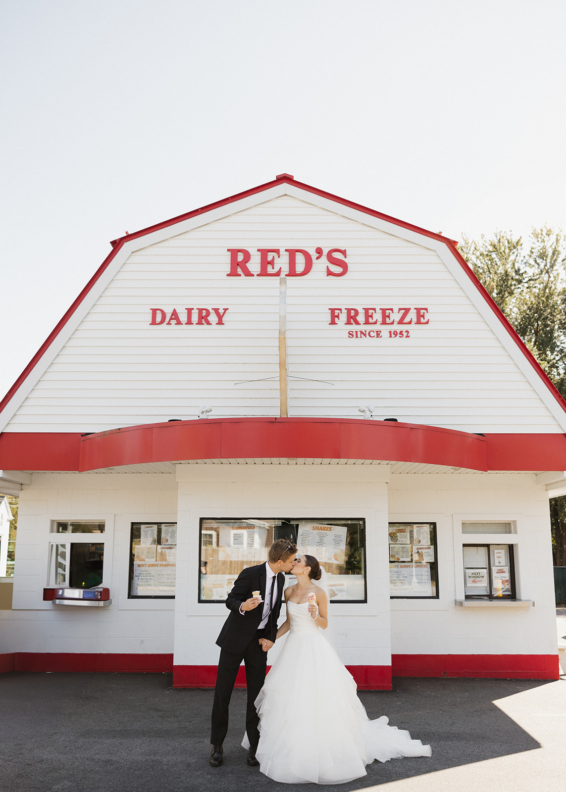 bride and groom share a kiss and ice cream outside Red's Dairy, a unique nontraditional wedding idea!