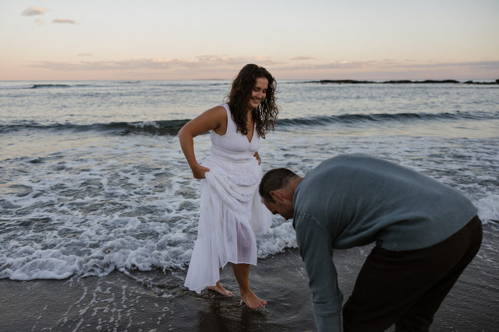 stunning couple pose for a photo on the beach during their East Coast beach engagement photoshoot