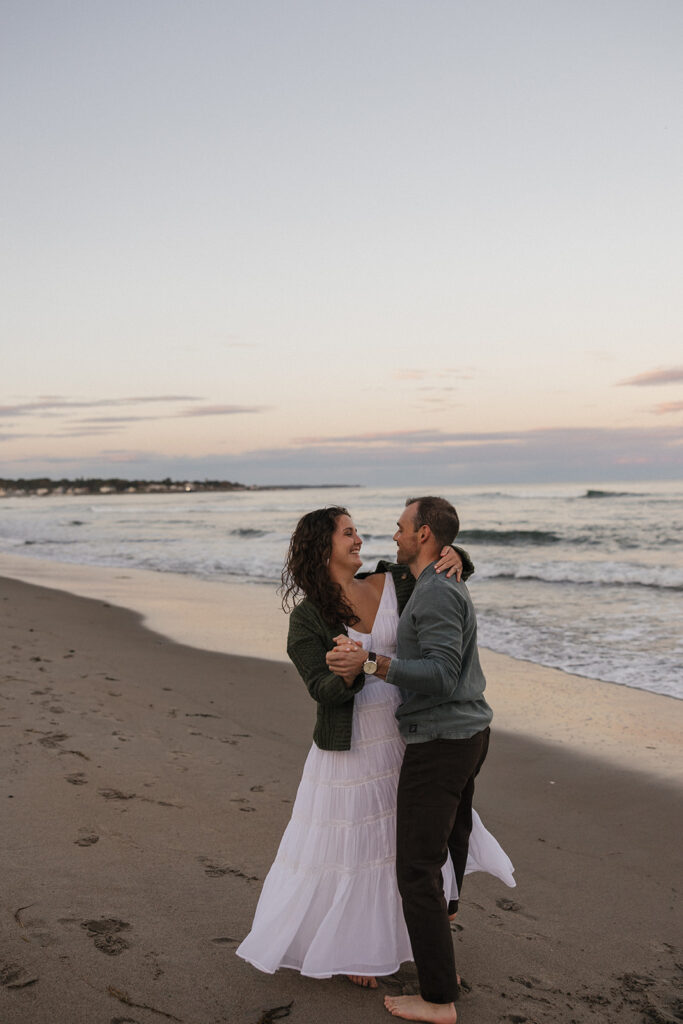 stunning couple pose for a photo on the beach during their East Coast beach engagement photoshoot