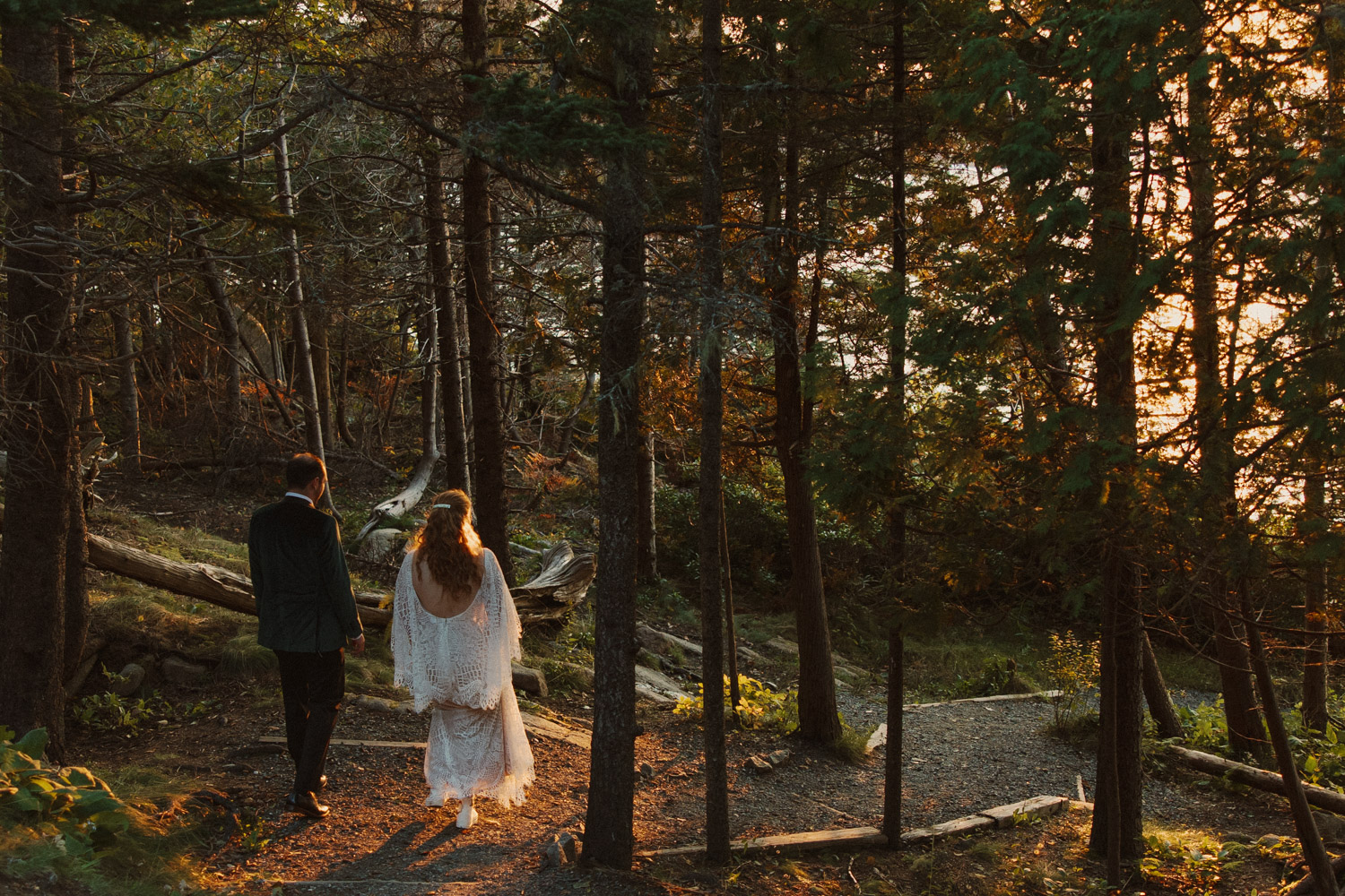 stunning bride and groom walk through the forest together during sunset