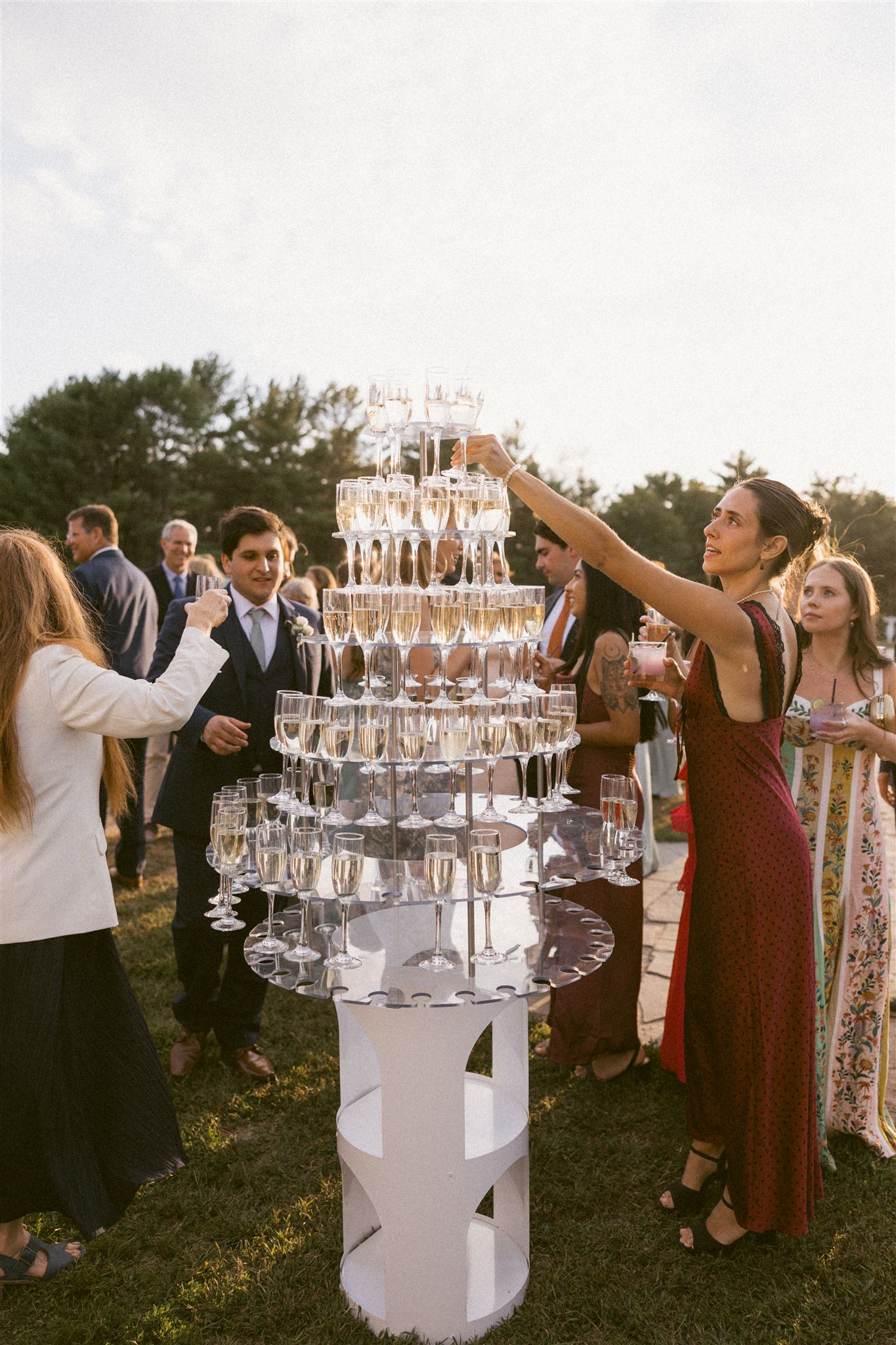 guests carefully take a glass from a champagne glass tower at a wedding reception