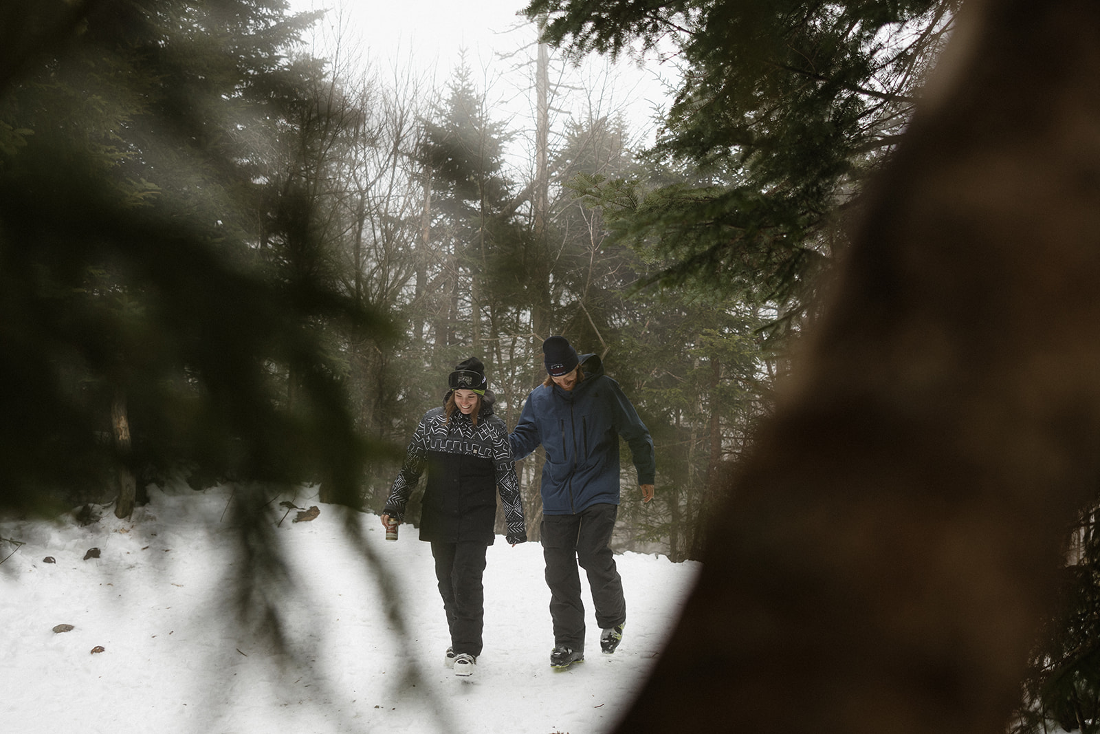 newly engaged couple walk through the woods together