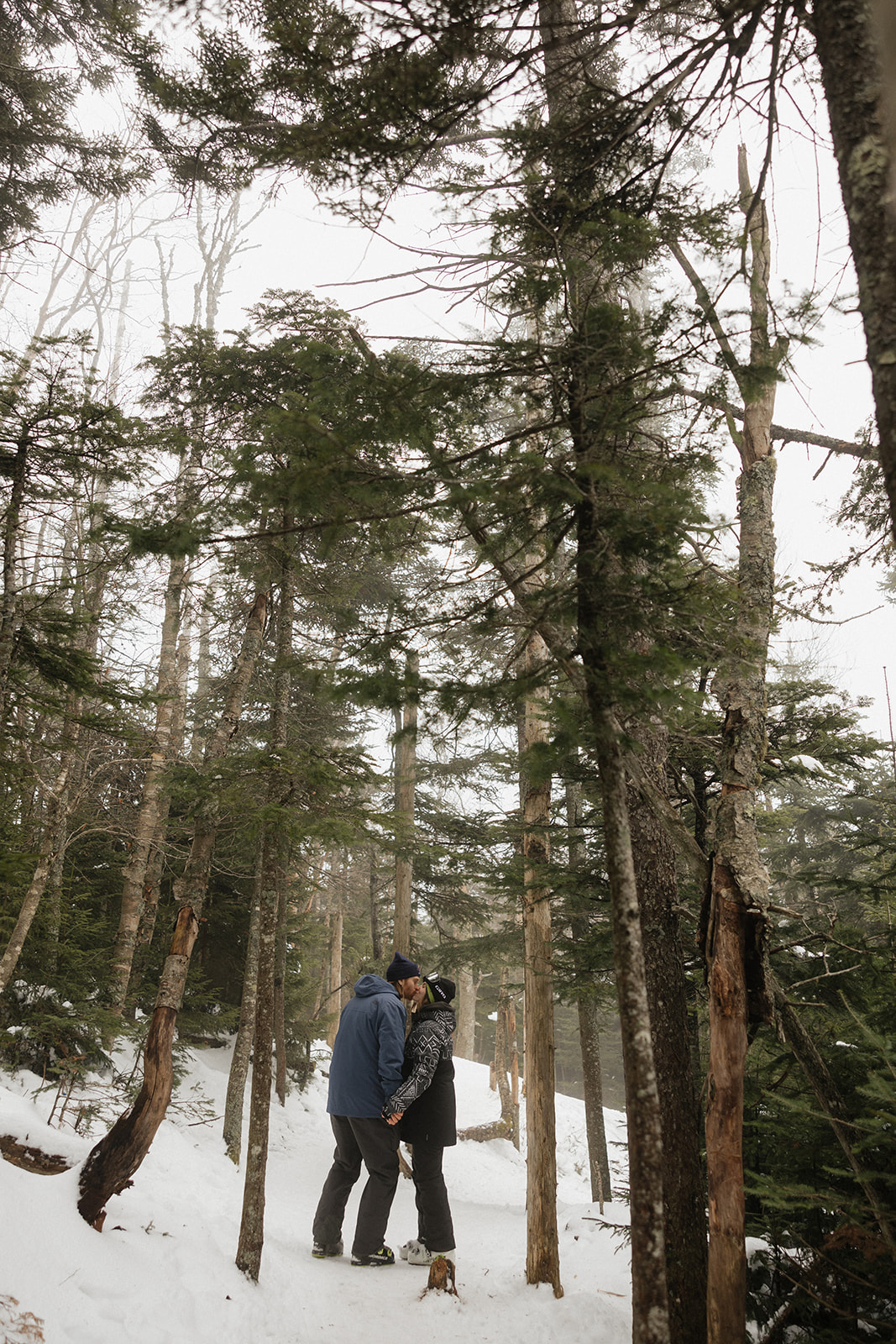 stunning couple pose in woods during their ski proposal