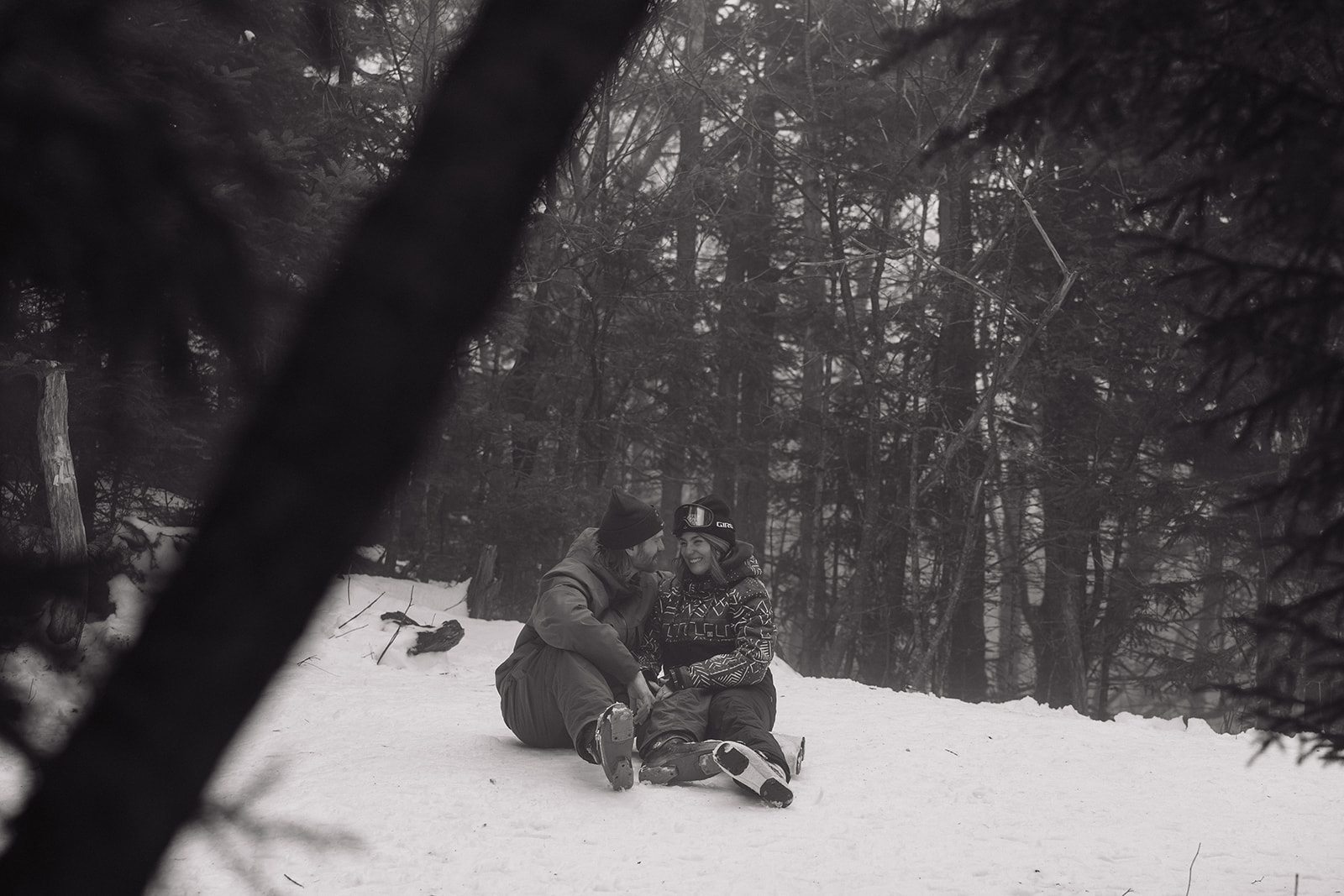 beautiful couple sit on the snow celebrating their ski proposal