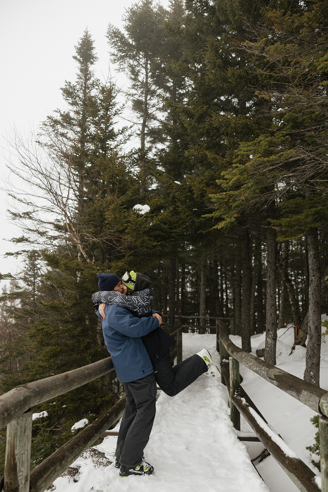 couple share a kiss in the snowy woods