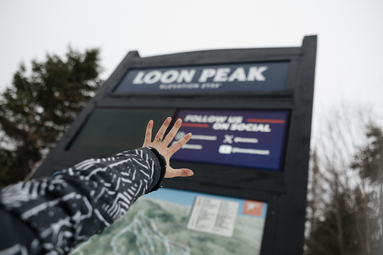 bride showcases her new ring with the Loon Peak sign in the background