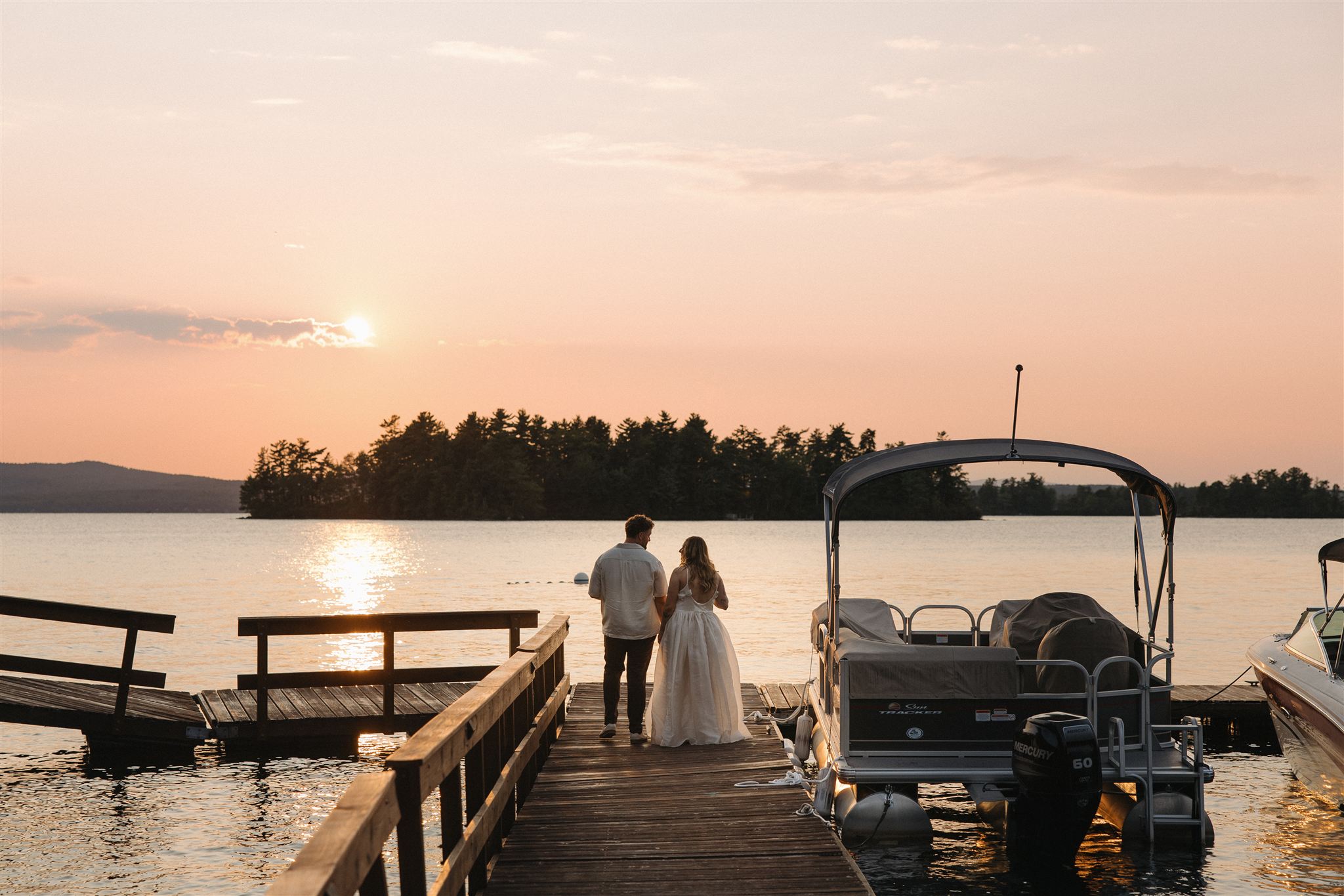 bride and groom share conversation as they look over the sunset over the lake