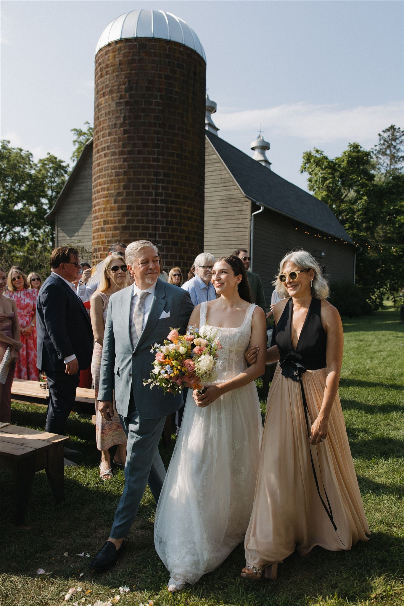 bride gets walked down the aisle by her mom and dad