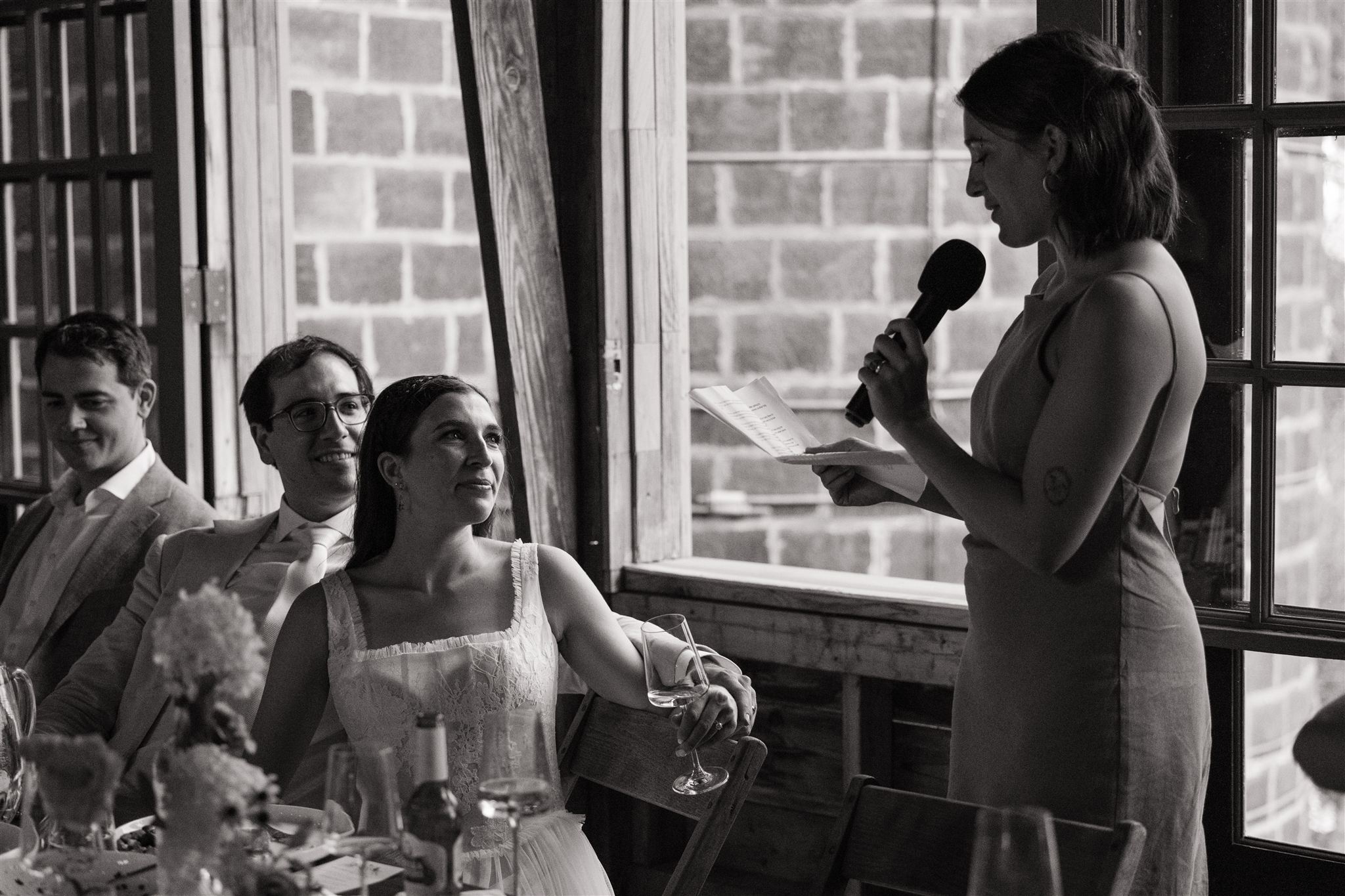 bride and groom listen as their siblings give speeches 