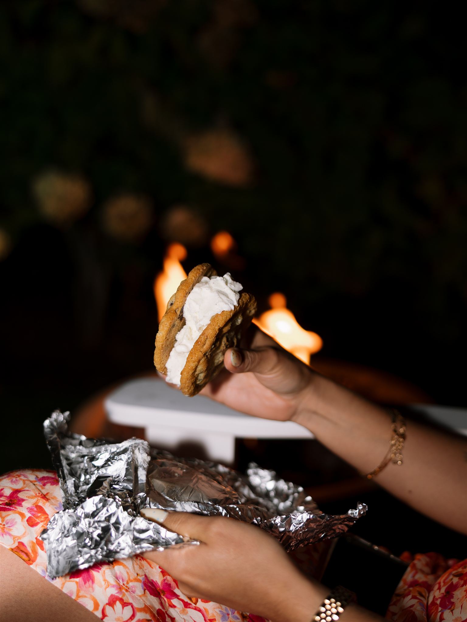 guest enjoys a chocolate chip ice cream sandwich by the fire