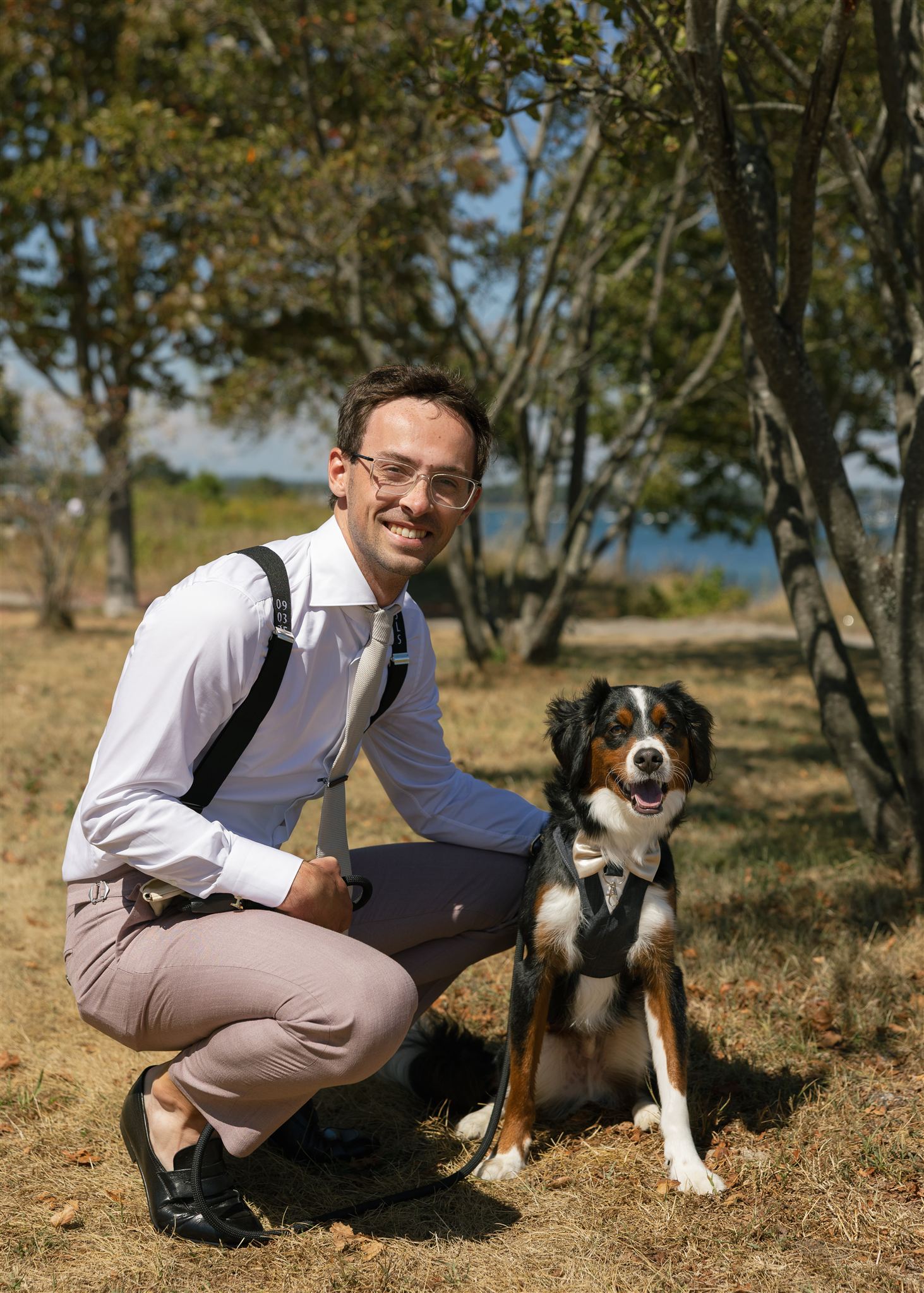 groom poses for a photo with the couples dog