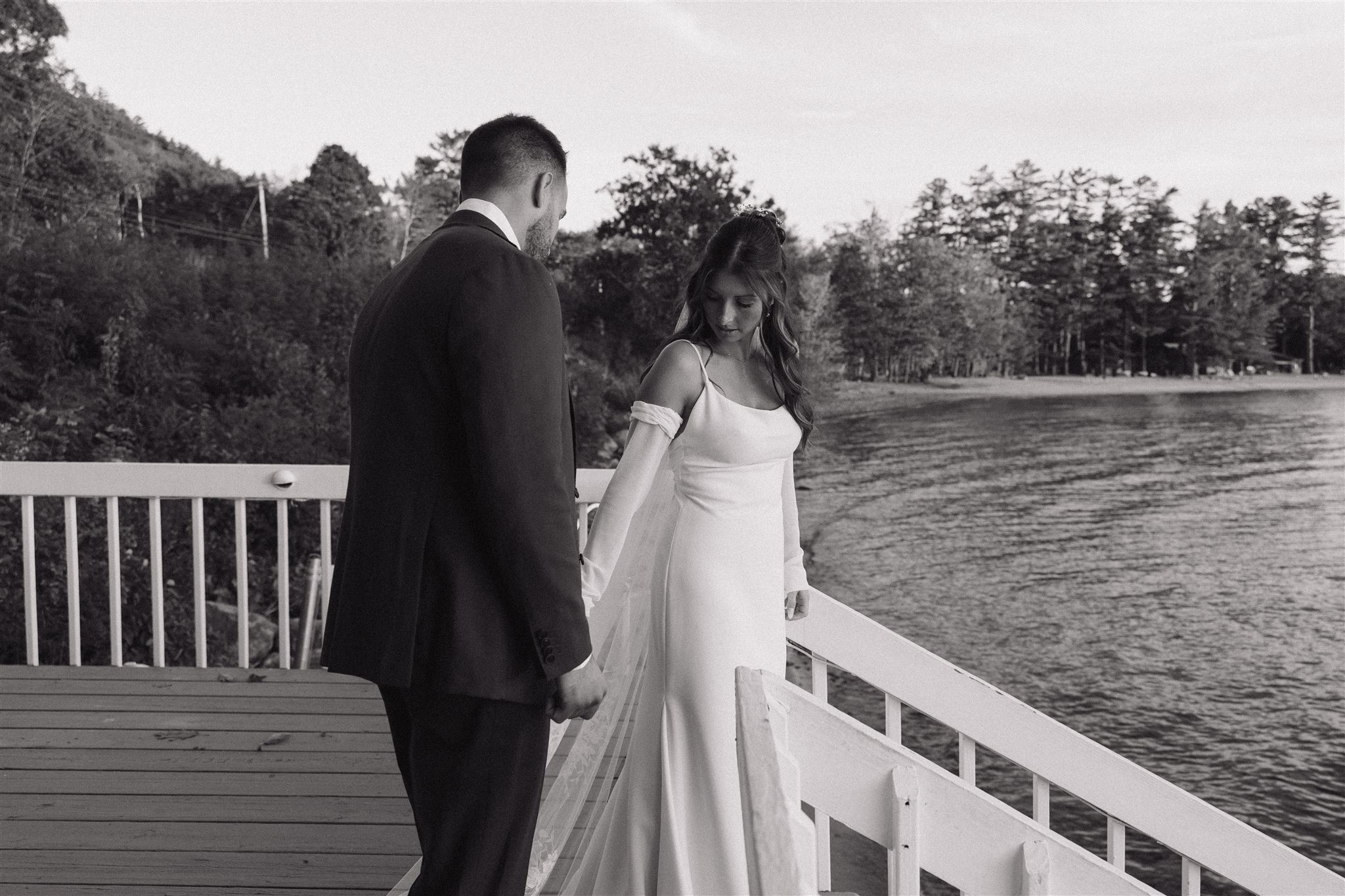 bride and groom candidly walking down to the lake at their lakes region nh wedding venue