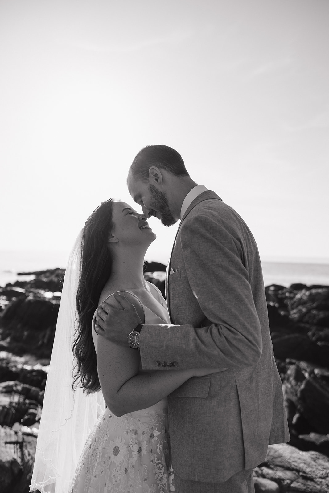 bride and groom share a kiss with the seacoast in the background